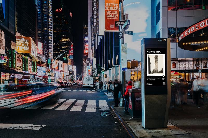 a nighttime cityscape with a kiosk displaying historic images